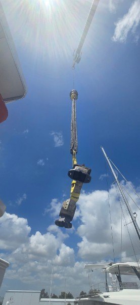 Marine diesel crankshaft suspended from crane during dockside service