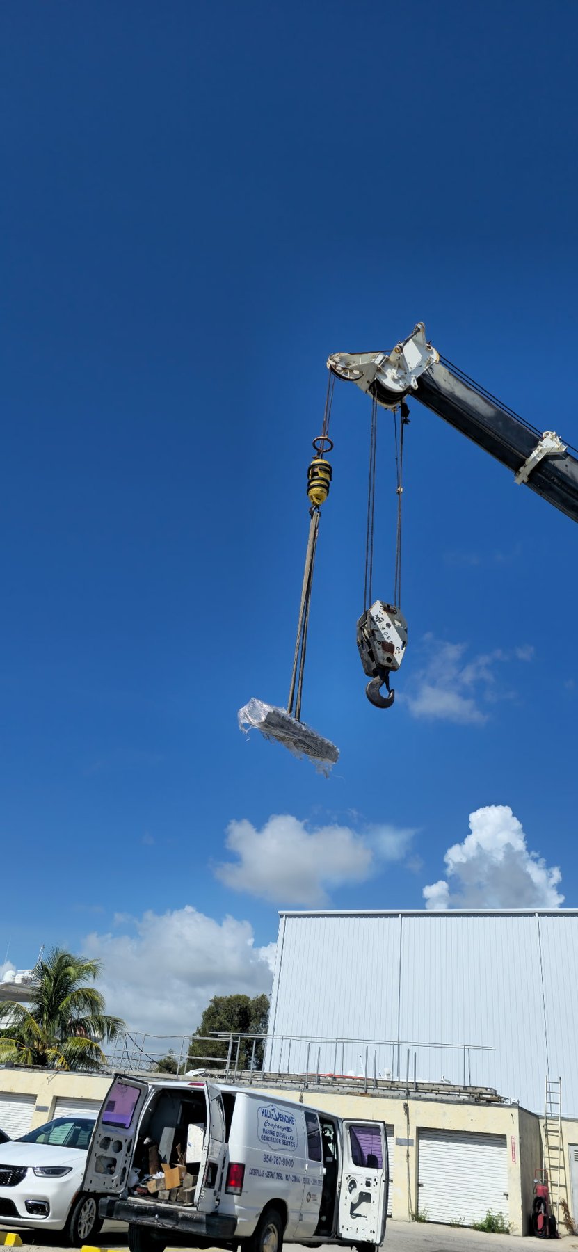 Crane-assisted marine equipment service with Hall Engine Company van