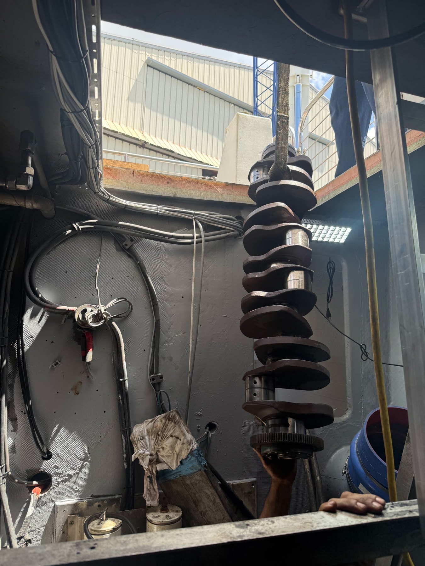 Marine diesel crankshaft being hoisted through yacht engine room access