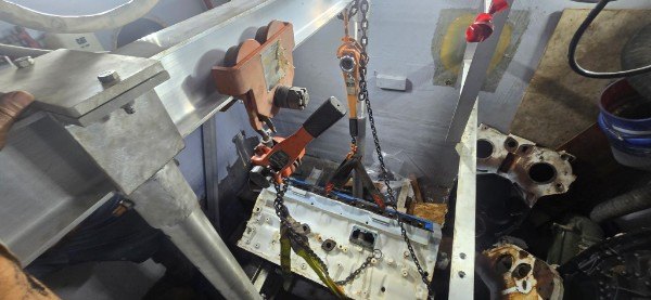 Marine diesel engine block supported by chain hoist during yacht service