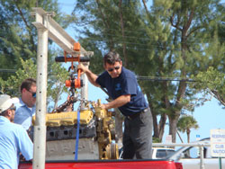 Hall Engine Company technician using a portable hoist to handle a marine diesel engine in a pickup truck