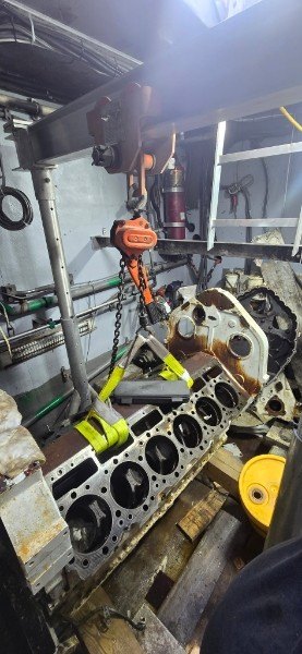 Marine diesel engine block lifted with chain hoist inside yacht engine room